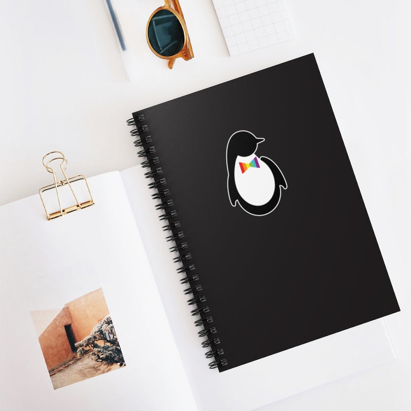 Black Spiral Bound Notebook with Dash of Pride Penguin Logo - Flat on Desk with Other Notebooks